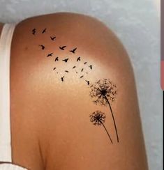 a woman's back with a dandelion tattoo on it