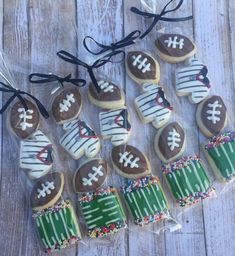 decorated cookies in the shape of footballs are tied up on a wooden table with string