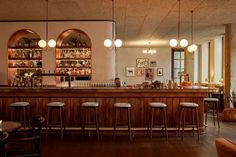 a bar with lots of stools and lights hanging from it's ceiling in a restaurant