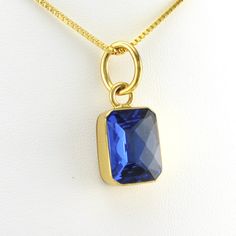 This lab created tanzanite rectangle gemstone is set in alchemía. Gem has a sparkly checkerboard cut. Pendant is 1 3/16 inches long and 1/2 inch wide and is sold separate from the 18k gold fill 1.2mm box chain shown. Alchemía a blend of base metals that looks like 18k gold and will not change color and is hypoallergenic. Style Number: 19209 Metal: Alchemía Gemstone: Lab Created Tanzanite Dimensions: 1 3/16 inches long and 1/2 inch wide Handmade in Mexico Gold Faceted Rectangular Stone Jewelry, Gold Faceted Rectangular Pendant Jewelry, Gold Faceted Jewelry With Rectangular Stone, Gold Tanzanite Jewelry With Faceted Design, Sapphire Gemstone Rectangular Necklace, Sapphire Gemstone Necklace In Rectangular Shape, Rectangular Sapphire Gemstone Necklace, Sapphire Rectangular Pendant Jewelry For Gift, Gold Faceted Rectangular Necklace