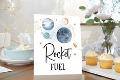 a card that says rocket fuel on it next to cupcakes and vase with flowers