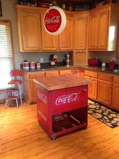 an old coca - cola cart is in the middle of a kitchen with wooden cabinets