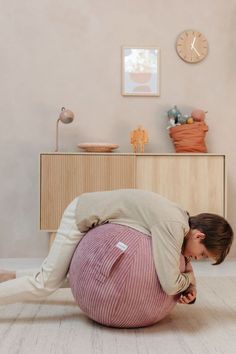 a woman laying on top of a pink ball in the middle of a living room