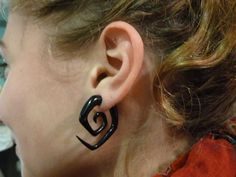 a close up of a person's ear with black metal earrings on top of it