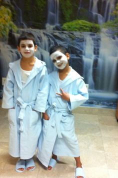 two young boys with face paint standing in front of a waterfall