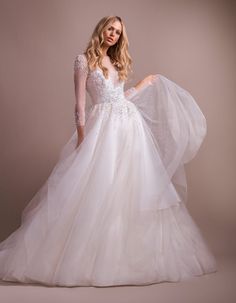 a woman in a white wedding dress with long sleeves and an open - back gown