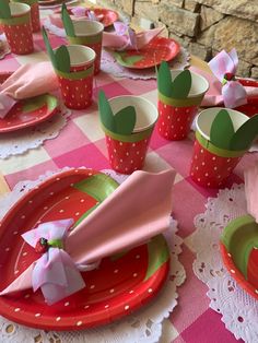 the table is set with pink and green plates, cups, napkins and utensils