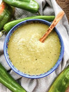 a blue bowl filled with sauce next to green beans and jalapeno peppers