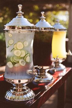 three silver cups filled with liquid and cucumbers