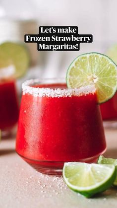 two glasses filled with red liquid and limes next to each other on a table