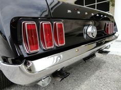 the rear end of a black mustang parked in front of a building