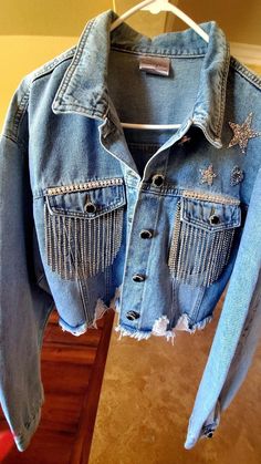 Sparkly, Country Glam, Rhinestone Crop, Distressed Jean Jacket. Perfect for Weekend Outings, Stage Coach, Coachella, Rodeo, Night Club, Parties, Night out, Daytime Excursions, Wineries, ect. Unique One of a kind, Made to Order, Custom Order Rhinestone, Bling Jacket. Super Cute and Unique! You'll get lots of Compliments! Fun to Wear! This Jacket is a large. I recently bought this denim jacket new, plain. I added all embellishments, crystal button covers, patch stars and heart, crystal crown on back, pearl and crystal trim, crystal, tassel fringe on front pockets.  Embellishments on fabric were attached using E6000, permanent bond, which is washer/dryer safe and button coverings down the front jacket and sleeve cuffs attached using Gem-Tac permanent bond. Last step is hand sewn with clear ny Denim Jacket With Tassels, Long Sleeve Denim Jacket With Rhinestone Fringe, Casual Denim Jacket With Rhinestone Fringe, Casual Long Sleeve Denim Jacket With Rhinestone Fringe, Bedazzled Jean Jacket, Bling Denim Jacket, Rhinestone Jean Jacket, Denim Jacket Crop, Western Denim Jacket