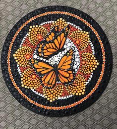 a black plate with orange butterflies painted on it