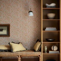 a wooden bench sitting next to a bookshelf filled with lots of books and pillows