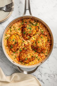 a pan filled with rice and meat covered in sauce on top of a marble counter