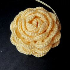 a crocheted flower is shown on a black surface