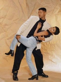 a man holding a woman on his back in front of a white sheeted backdrop