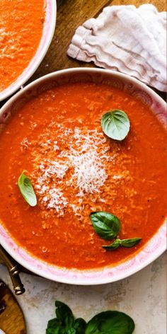 two bowls of tomato soup with basil sprinkled on top