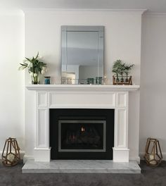 a living room with a fire place and potted plants on the fireplace mantel