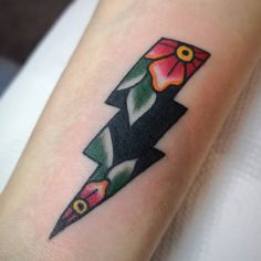 a tattoo on the arm of a woman with an arrow and flowers in its center