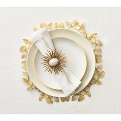 a white plate topped with gold leaves next to a napkin on top of a table