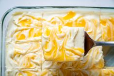 a spoon is lifting some cake batter out of the baking dish with icing on it