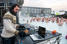 a man standing in front of a laptop computer next to a pool filled with people