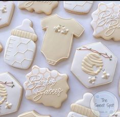 baby shower cookies are laid out on a white tablecloth with the names and designs