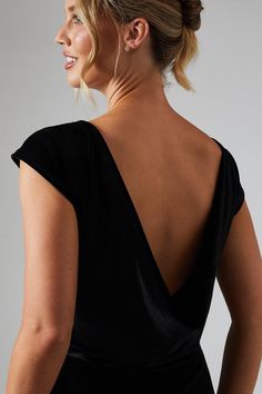 a woman in a black dress with her back turned to the camera, looking off into the distance