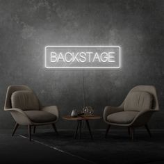 two chairs and a table in front of a green wall with the words backstage on it