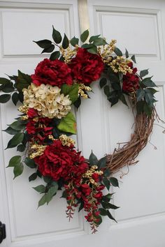 a wreath with red and white flowers hanging on a door