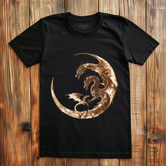 a black t - shirt with gold dragon on the front and back, against a wooden background