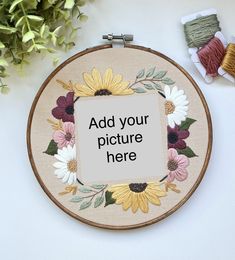 a cross stitch pattern with flowers on it and some spools of thread next to it