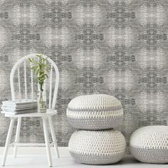 two white stools sitting next to each other in front of a wall with a pattern on it