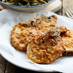 three fried food items on a plate next to a bowl of green beans