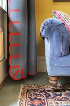 a blue chair sitting in front of a window next to a rug on the floor