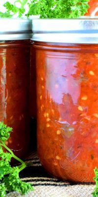 two jars filled with red sauce and garnished with parsley on the side