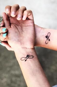 two people holding hands with tattoos on their wrist and the other hand has scissors in it