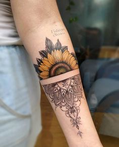 a woman's arm with a sunflower tattoo on it