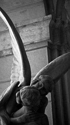 an angel statue with its wings spread over it's head and back facing the viewer