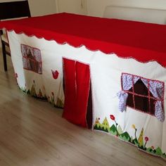 a red and white table cloth on top of a bed covered in a house design