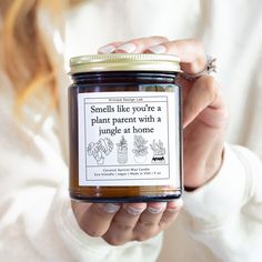 a woman holding a jar of honey with a label that says smells like you're a plant parent with a jungle at home