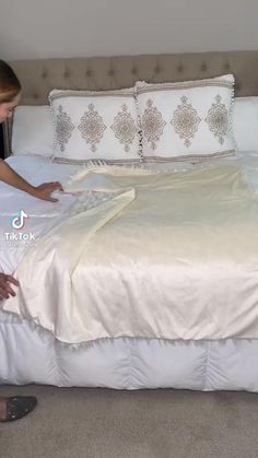 a woman in black shirt laying on bed with white comforter and pillowcases