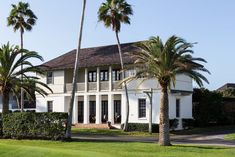 a large white house with palm trees in front