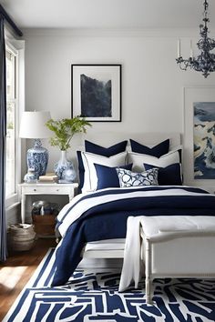 a bedroom with blue and white decor on the walls, bed linens in dark blue and white