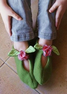 a child's feet wearing green slippers with flowers on them