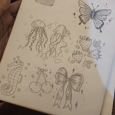 a hand holding a notebook with drawings of sea animals and jellyfishs on it