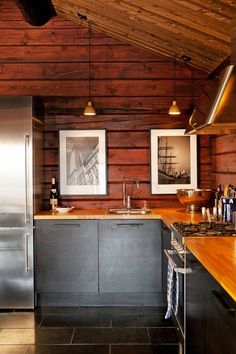 a kitchen with wood paneling and stainless steel appliances in the center, along with two pictures on the wall