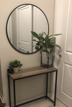 a mirror on the wall next to a table with a potted plant in it