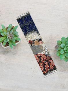 a needled bookmark next to some succulents and a potted plant